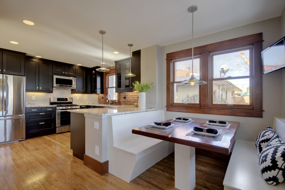 Example of a mid-sized eclectic light wood floor and brown floor eat-in kitchen design in Denver with stainless steel appliances, shaker cabinets, dark wood cabinets, red backsplash, brick backsplash and a peninsula