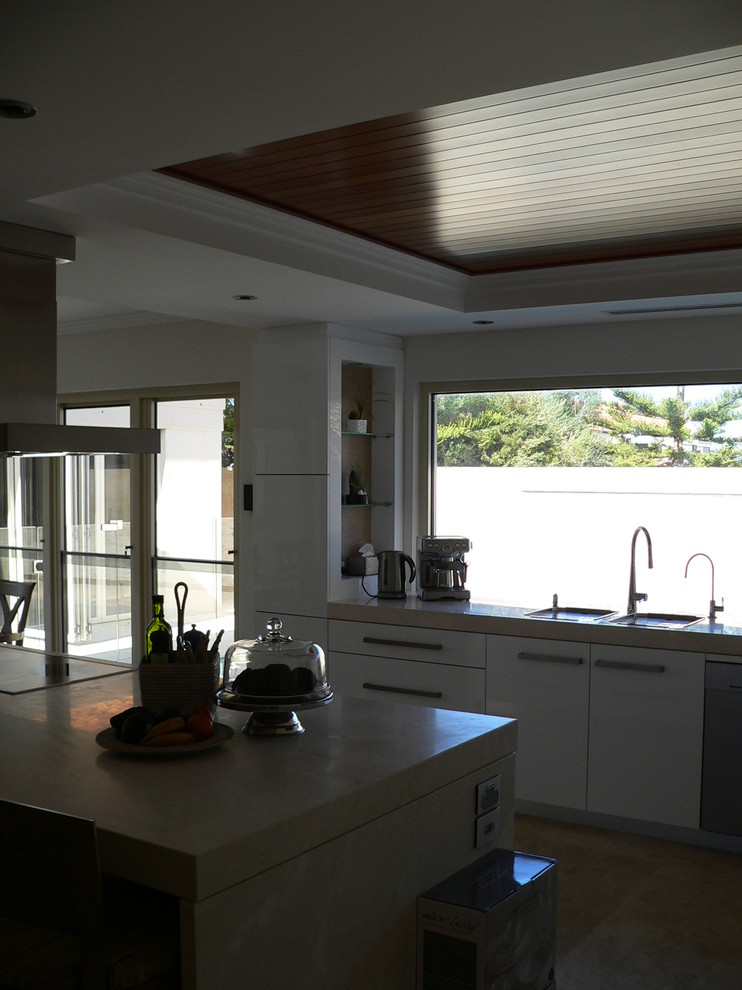 Idéer för ett stort maritimt kök, med en undermonterad diskho, vita skåp, marmorbänkskiva, svarta vitvaror, travertin golv och en köksö