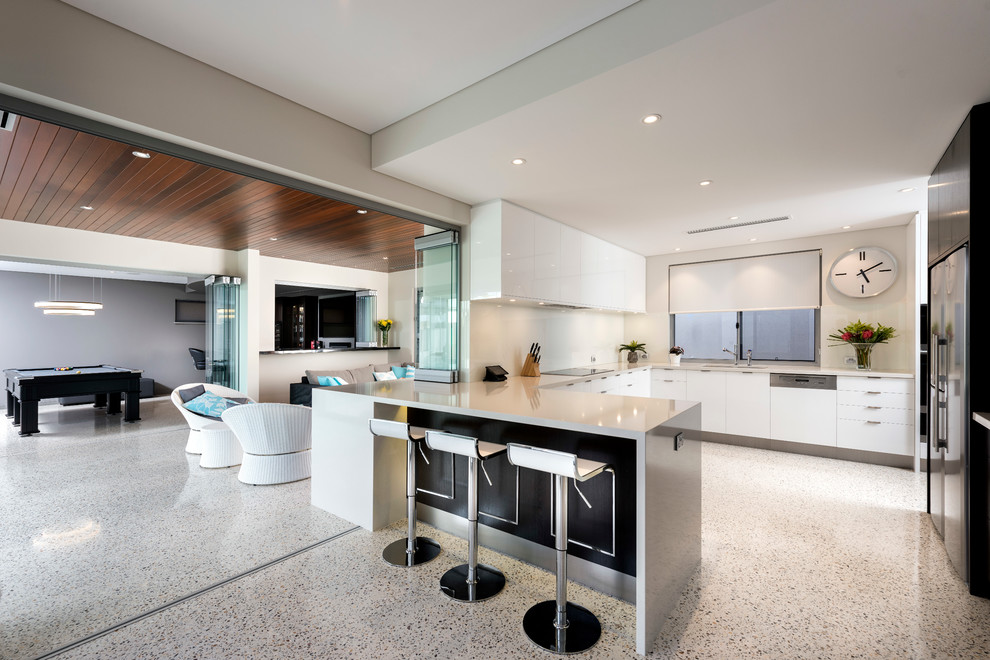Design ideas for a large modern u-shaped enclosed kitchen in Perth with a submerged sink, flat-panel cabinets, white cabinets, engineered stone countertops, white splashback, glass tiled splashback, stainless steel appliances, concrete flooring and an island.