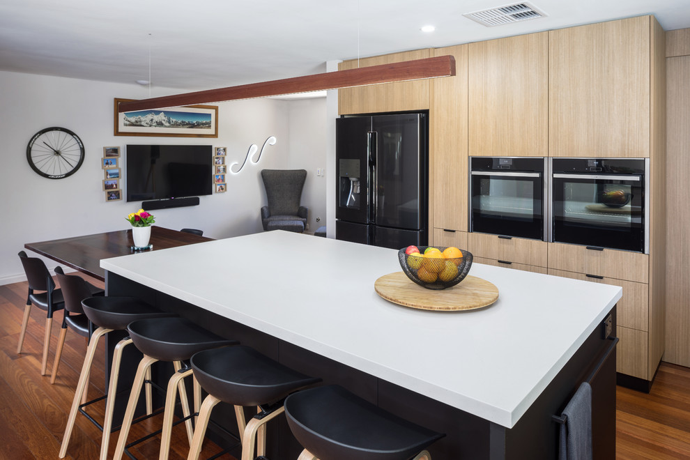 Ispirazione per un cucina con isola centrale moderno con ante lisce, ante in legno chiaro, top in quarzo composito e top grigio