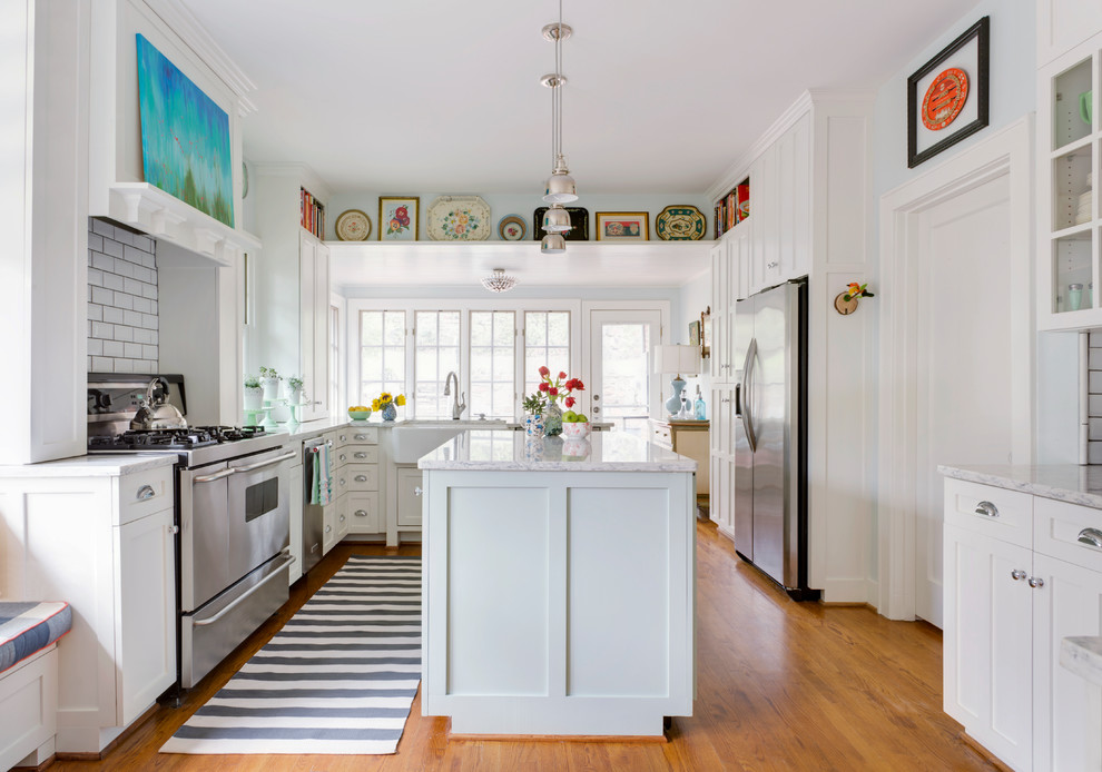 Inspiration for an eclectic u-shaped medium tone wood floor and brown floor kitchen remodel in Little Rock with shaker cabinets, white cabinets, white backsplash, subway tile backsplash, an island and gray countertops