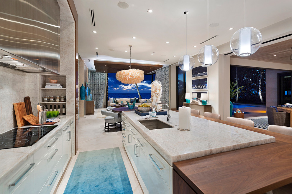 Immagine di una cucina costiera con lavello sottopiano, ante lisce, ante beige, paraspruzzi grigio, pavimento beige e elettrodomestici in acciaio inossidabile