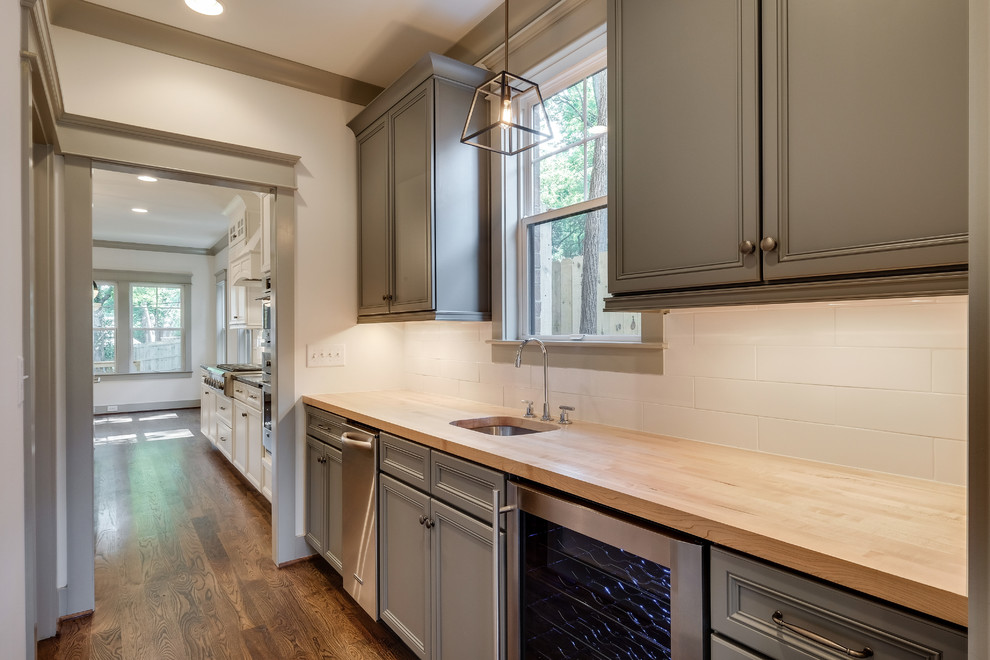Large elegant l-shaped medium tone wood floor kitchen pantry photo in Nashville with an undermount sink, recessed-panel cabinets, gray cabinets, wood countertops, white backsplash, subway tile backsplash and stainless steel appliances