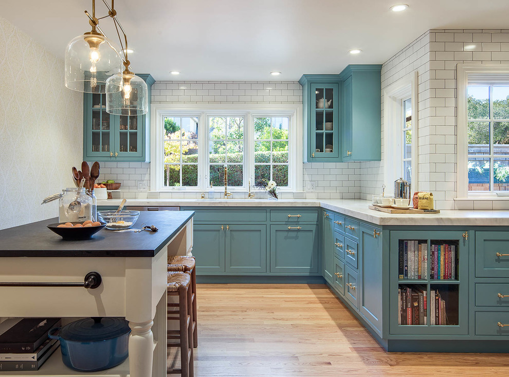 Foto de cocina clásica grande con puertas de armario azules, encimera de mármol, salpicadero blanco, suelo de madera en tonos medios, una isla, salpicadero de azulejos de piedra, fregadero bajoencimera y armarios estilo shaker