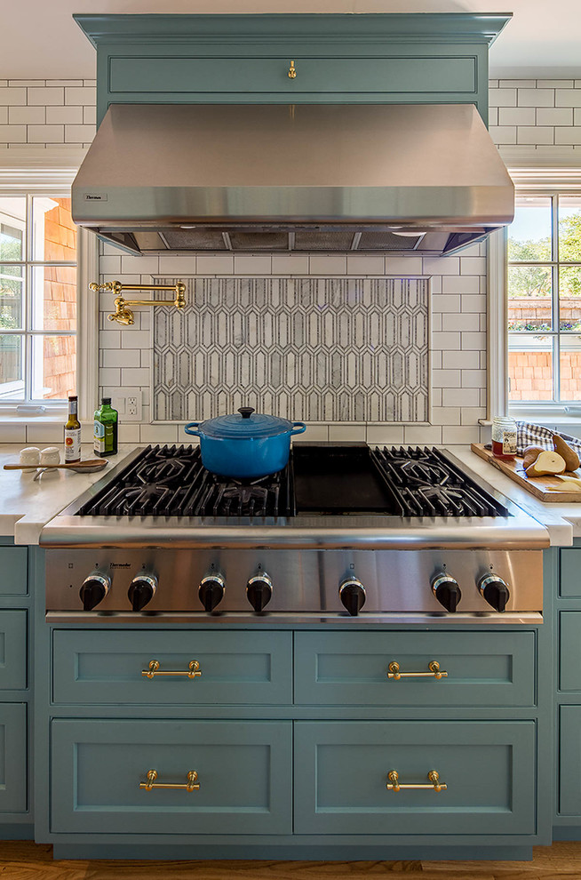 Inspiration för ett stort funkis l-kök, med luckor med infälld panel, blå skåp, marmorbänkskiva, vitt stänkskydd, stänkskydd i stenkakel, rostfria vitvaror, mellanmörkt trägolv och en köksö