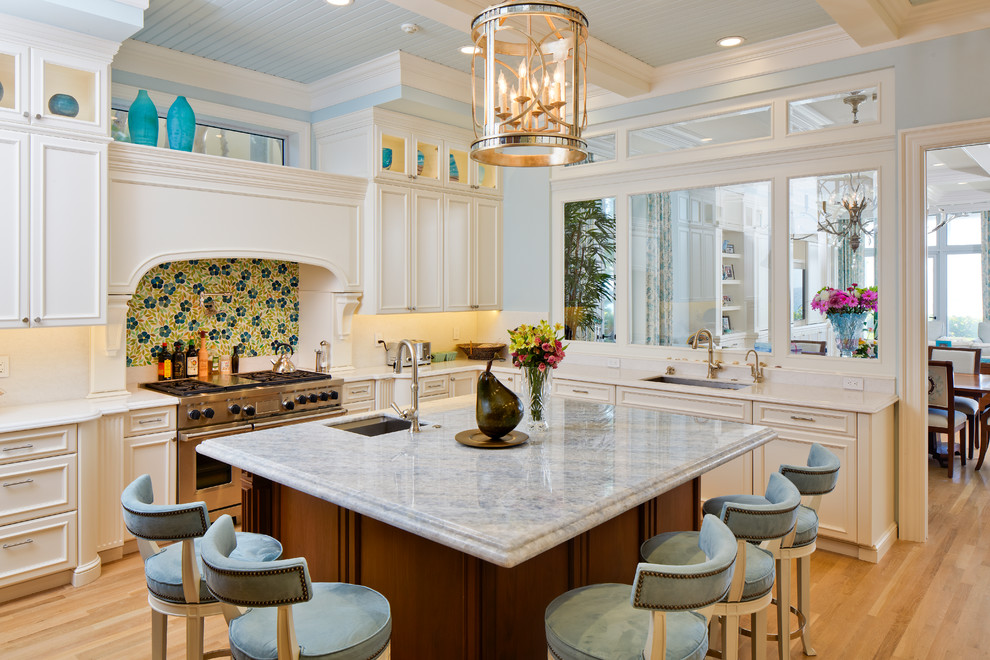 Design ideas for a coastal kitchen in Miami with a submerged sink, recessed-panel cabinets, stainless steel appliances, medium hardwood flooring and an island.