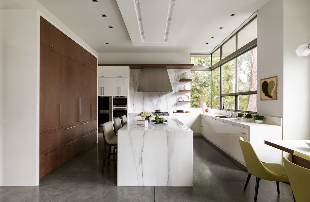 Inredning av ett modernt stort vit vitt kök, med en enkel diskho, släta luckor, marmorbänkskiva, vitt stänkskydd, stänkskydd i marmor, rostfria vitvaror, betonggolv, en köksö och grått golv