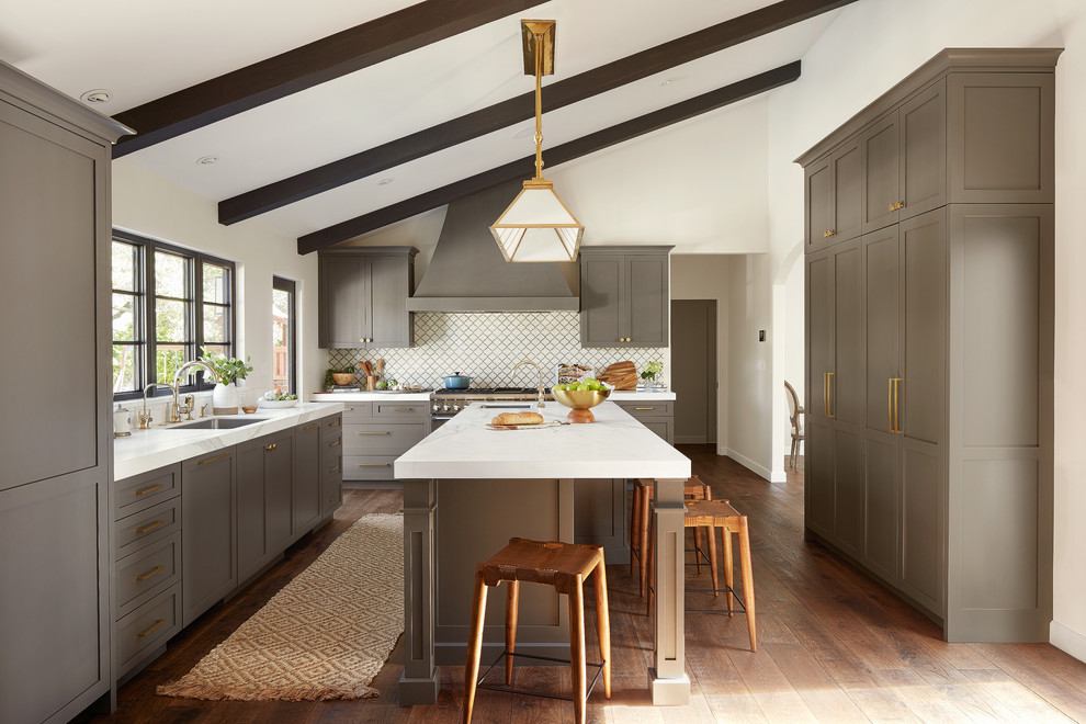 Example of a tuscan u-shaped dark wood floor and brown floor kitchen design in San Francisco with an undermount sink, shaker cabinets, gray cabinets, white backsplash, an island and white countertops