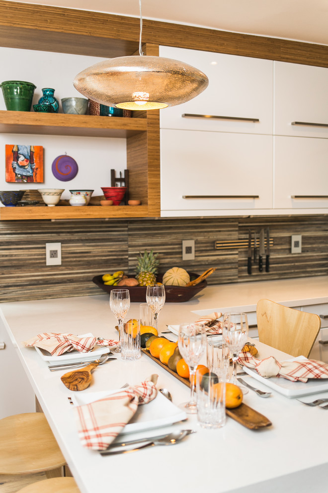 Bild på ett litet eklektiskt kök, med en undermonterad diskho, släta luckor, vita skåp, bänkskiva i kvarts, stänkskydd med metallisk yta, stänkskydd i porslinskakel, rostfria vitvaror, mellanmörkt trägolv och en halv köksö