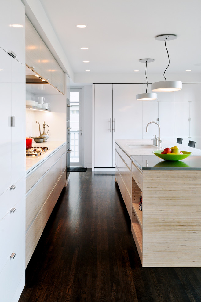 This is an example of a contemporary galley kitchen/diner in Seattle with a submerged sink, flat-panel cabinets, white cabinets, marble worktops, white splashback, stone slab splashback and stainless steel appliances.