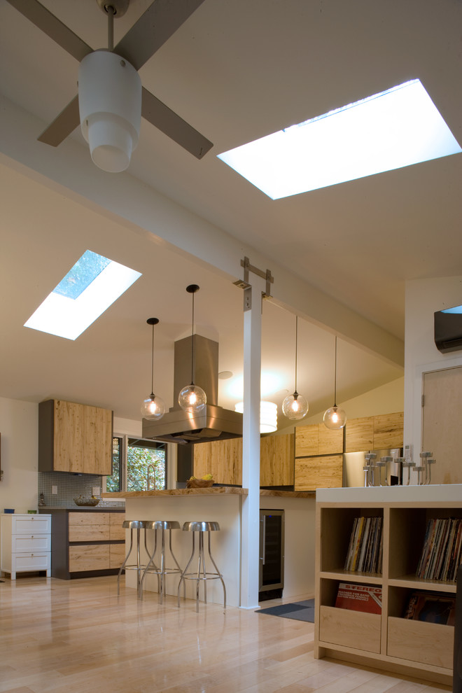 Example of a large mid-century modern u-shaped light wood floor eat-in kitchen design in Other with stainless steel appliances, a farmhouse sink, flat-panel cabinets, light wood cabinets, solid surface countertops, gray backsplash, mosaic tile backsplash and a peninsula