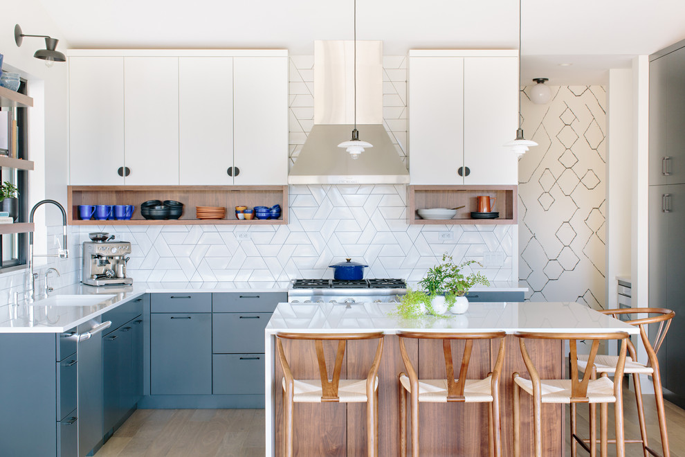 Esempio di una cucina minimal con lavello sottopiano, ante lisce, ante blu, paraspruzzi bianco, elettrodomestici in acciaio inossidabile, pavimento in legno massello medio, pavimento marrone e top bianco