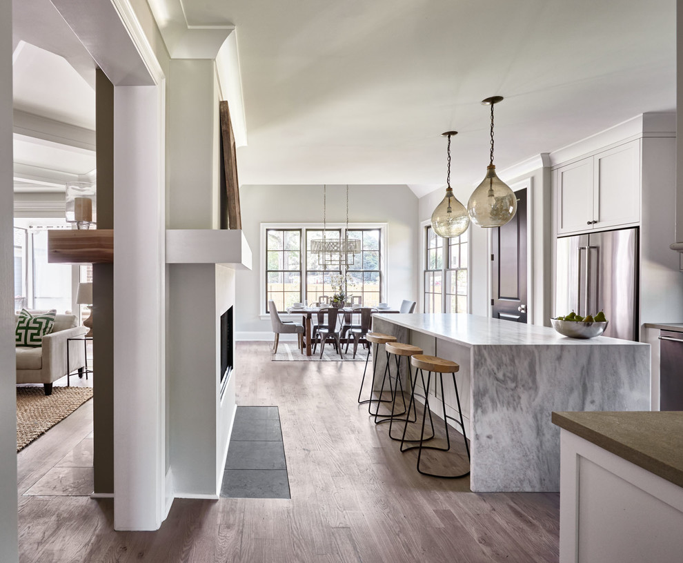 Inspiration for a large contemporary l-shaped medium tone wood floor open concept kitchen remodel in Charlotte with an undermount sink, white cabinets, quartzite countertops, gray backsplash, stainless steel appliances and an island