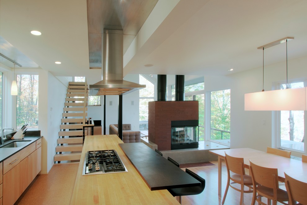 Immagine di una cucina abitabile minimalista con ante lisce, ante in legno chiaro e top in legno
