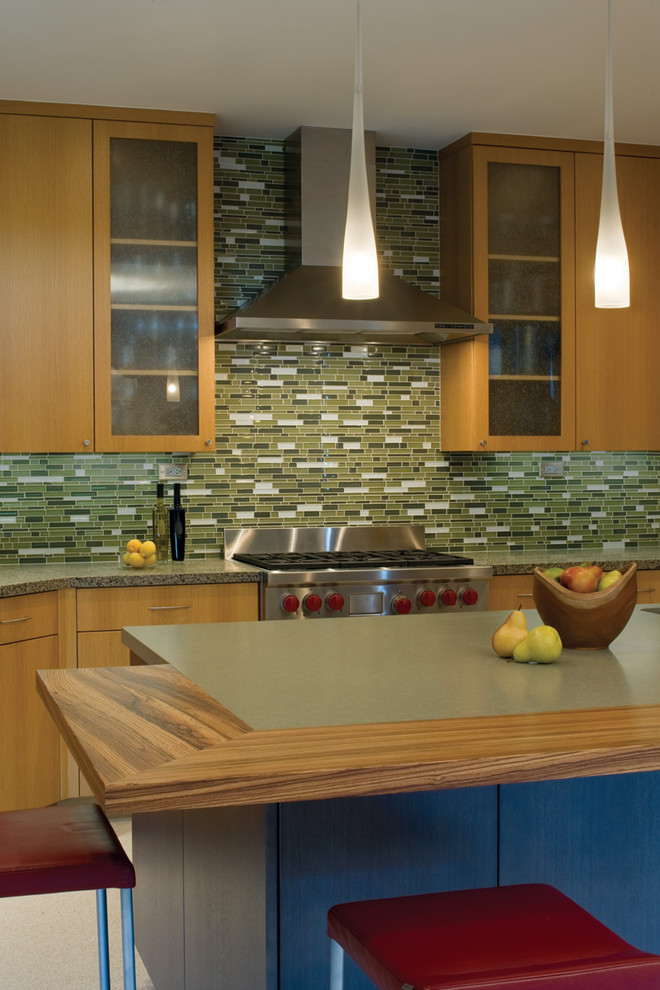 На фото: кухня в стиле модернизм с плоскими фасадами, фартуком из удлиненной плитки, зеленым фартуком и фасадами цвета дерева среднего тона