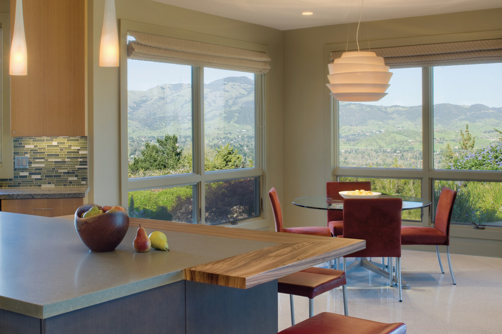Стильный дизайн: кухня в стиле модернизм с обеденным столом, светлыми деревянными фасадами, разноцветным фартуком и фартуком из удлиненной плитки - последний тренд