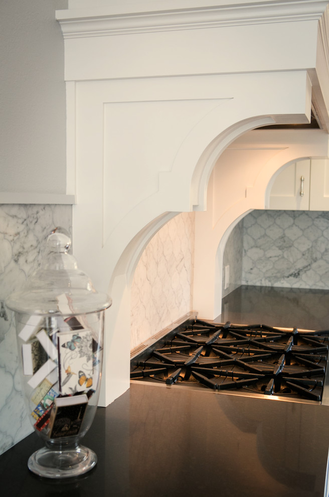Klassisk inredning av ett mellanstort kök, med en köksö, skåp i shakerstil, vita skåp, bänkskiva i kvarts, vitt stänkskydd, stänkskydd i mosaik, rostfria vitvaror, en undermonterad diskho och mörkt trägolv