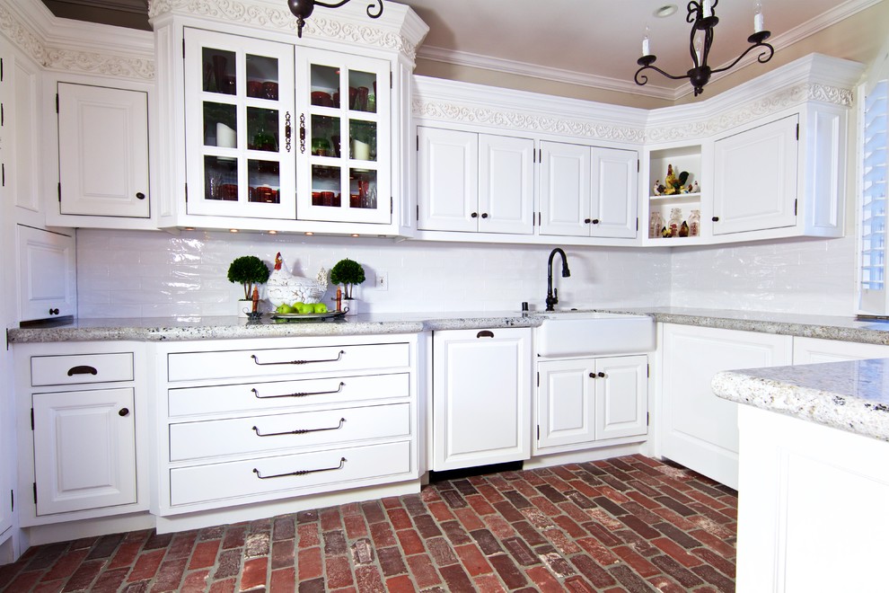 Large trendy u-shaped brick floor and red floor eat-in kitchen photo in Orange County with a farmhouse sink, raised-panel cabinets, white cabinets, granite countertops, white backsplash, subway tile backsplash, stainless steel appliances and an island