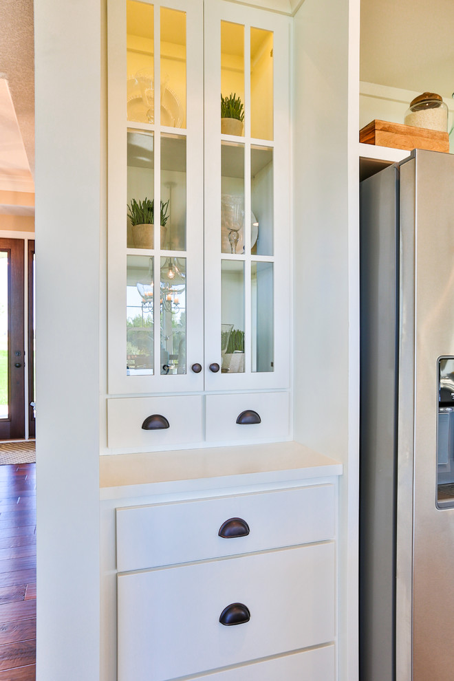 Modelo de cocina actual de tamaño medio con armarios tipo vitrina, puertas de armario blancas, encimera de madera y electrodomésticos de acero inoxidable