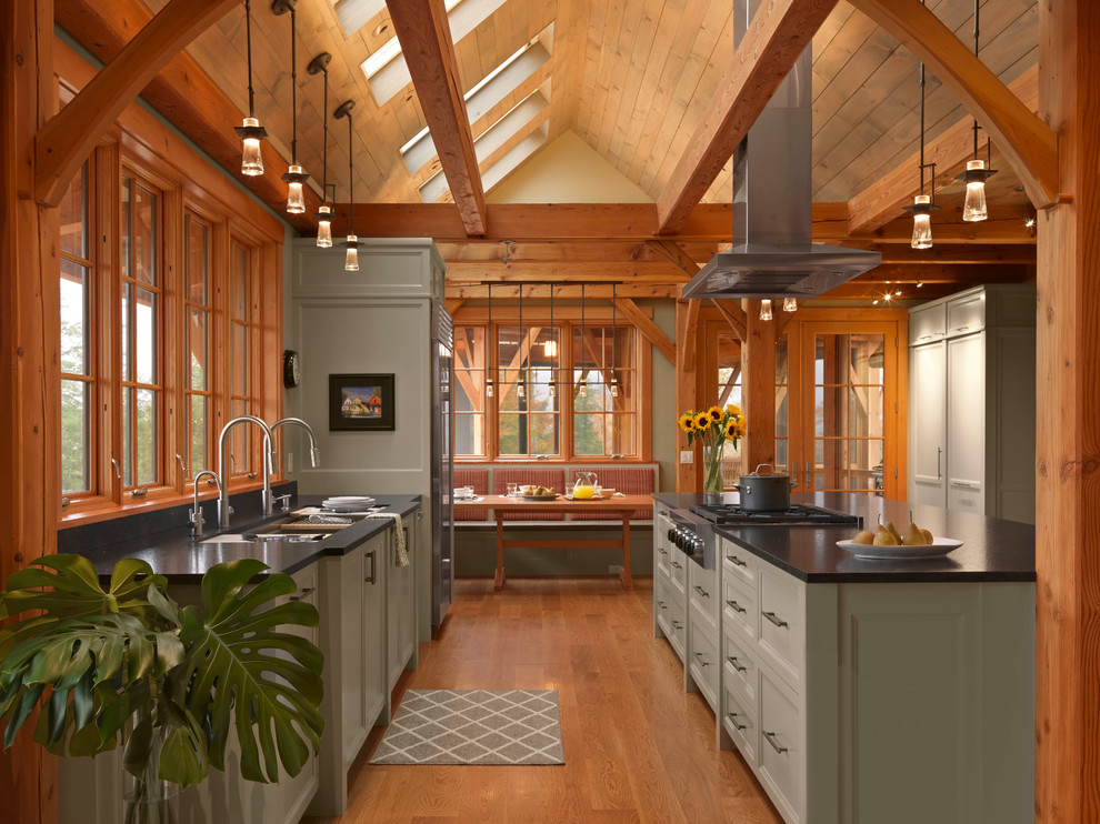 Immagine di una cucina stile rurale con lavello sottopiano, ante con riquadro incassato, ante verdi, elettrodomestici in acciaio inossidabile, pavimento in legno massello medio e top nero