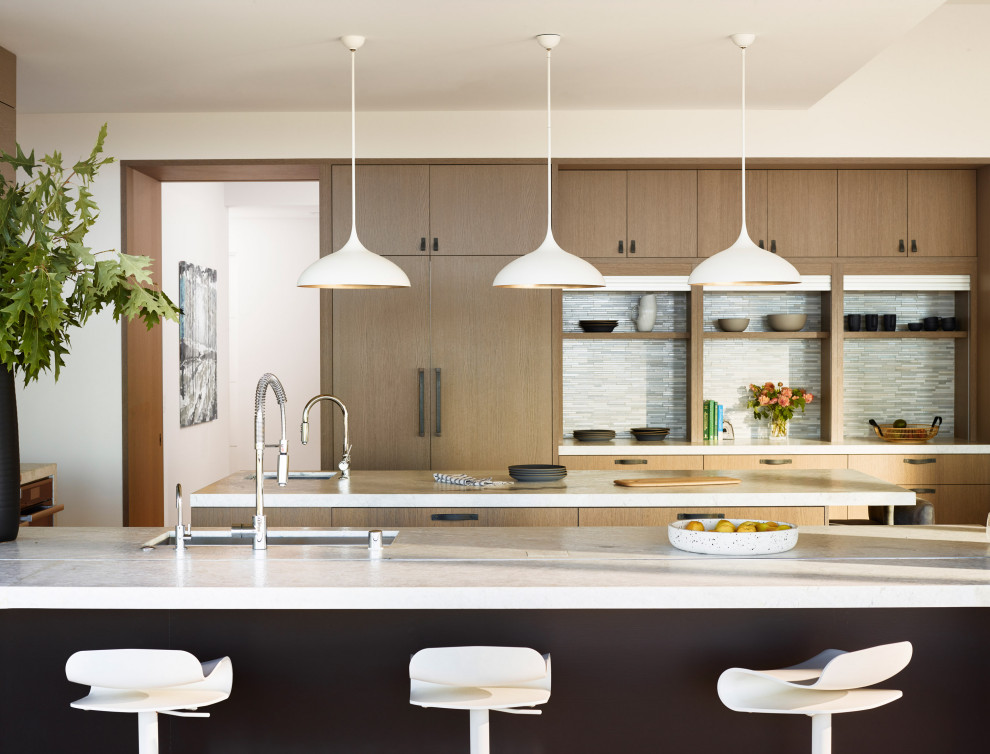 Transitional u-shaped light wood floor eat-in kitchen photo in San Francisco with a drop-in sink, flat-panel cabinets, medium tone wood cabinets, quartzite countertops, gray backsplash, stainless steel appliances, an island and white countertops