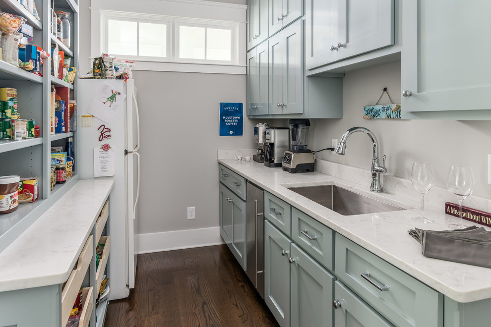 Traditional kitchen pantry in Nashville with shaker cabinets, blue cabinets, engineered stone countertops, white splashback, stainless steel appliances, medium hardwood flooring and white worktops.
