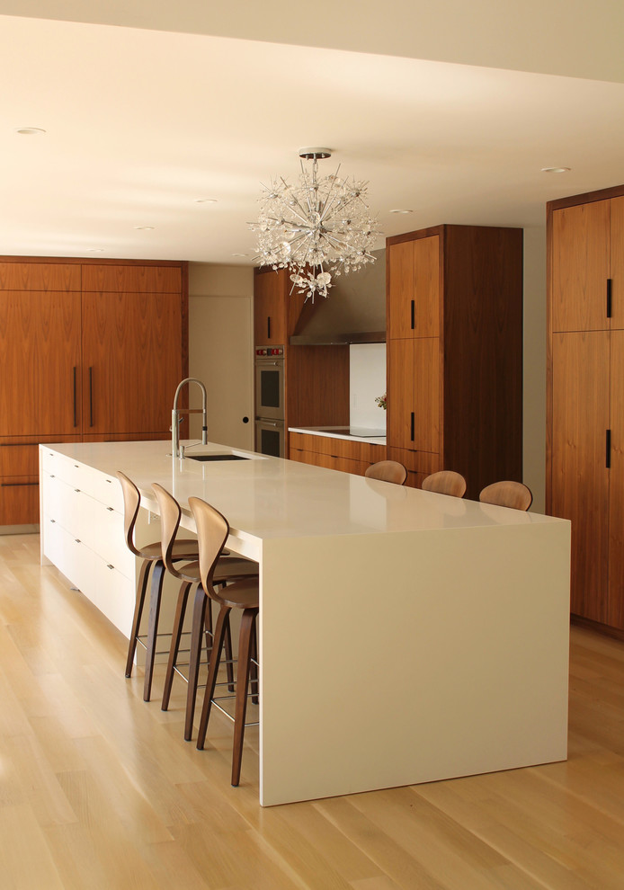 Eat-in kitchen - modern u-shaped light wood floor eat-in kitchen idea in New York with an undermount sink, flat-panel cabinets, medium tone wood cabinets, laminate countertops, stainless steel appliances and an island