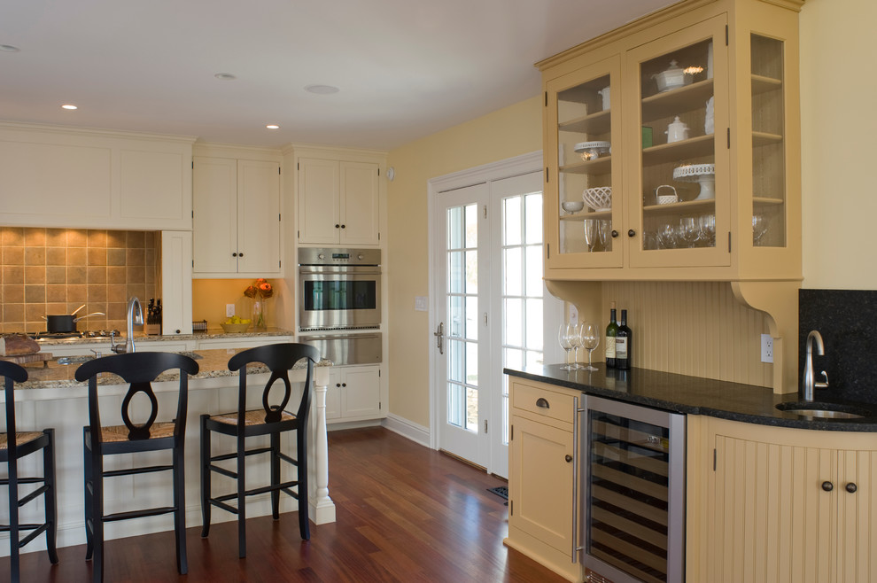 Bild på ett mellanstort vintage kök, med en undermonterad diskho, luckor med infälld panel, vita skåp, träbänkskiva, grått stänkskydd, stänkskydd i stenkakel, rostfria vitvaror, mellanmörkt trägolv och en köksö
