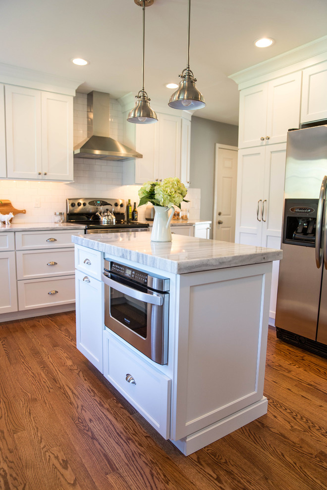 Large transitional l-shaped medium tone wood floor open concept kitchen photo in Philadelphia with an undermount sink, shaker cabinets, white cabinets, quartzite countertops, white backsplash, ceramic backsplash, stainless steel appliances and an island