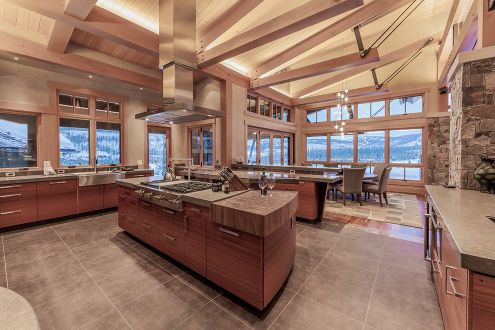 Foto på ett stort funkis kök, med släta luckor, bruna skåp, rostfria vitvaror, kalkstensgolv och flera köksöar
