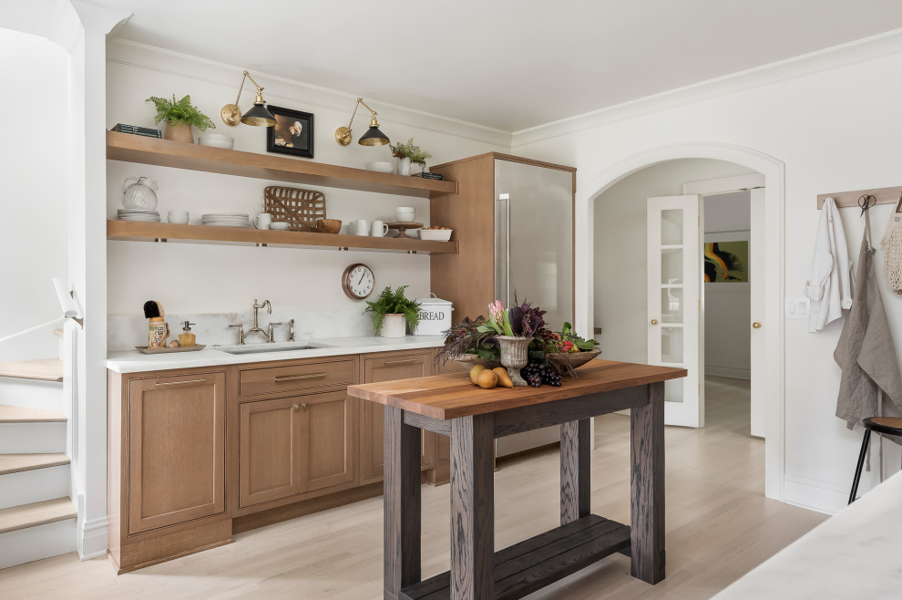 Inspiration for a medium sized traditional galley enclosed kitchen in Chicago with a built-in sink, beaded cabinets, medium wood cabinets, marble worktops, metallic splashback, mirror splashback, stainless steel appliances, light hardwood flooring, an island, brown floors and white worktops.