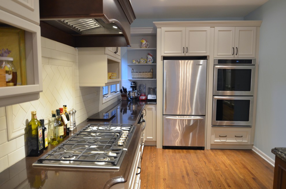 Bild på ett stort vintage kök, med en undermonterad diskho, luckor med upphöjd panel, vita skåp, bänkskiva i kvarts, vitt stänkskydd, stänkskydd i keramik, rostfria vitvaror, mellanmörkt trägolv och en köksö