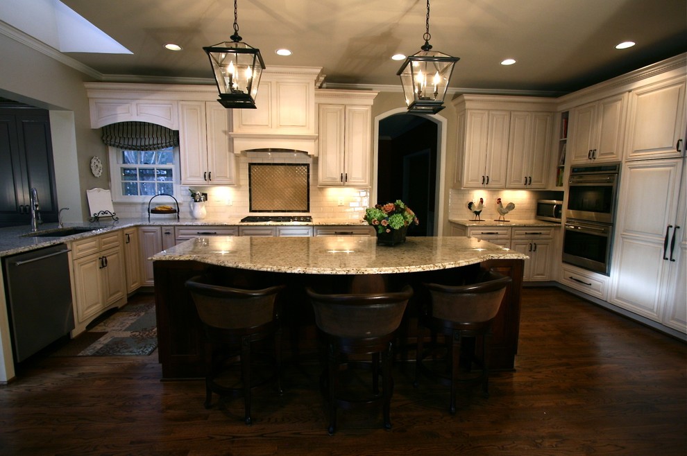 Exempel på ett stort klassiskt u-kök, med en köksö, en undermonterad diskho, luckor med upphöjd panel, vita skåp, granitbänkskiva, vitt stänkskydd, stänkskydd i tunnelbanekakel, rostfria vitvaror och mörkt trägolv