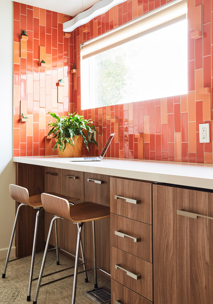 This is an example of a medium sized contemporary galley enclosed kitchen in Los Angeles with a single-bowl sink, glass-front cabinets, medium wood cabinets, engineered stone countertops, orange splashback, ceramic splashback, stainless steel appliances, porcelain flooring, no island and grey floors.