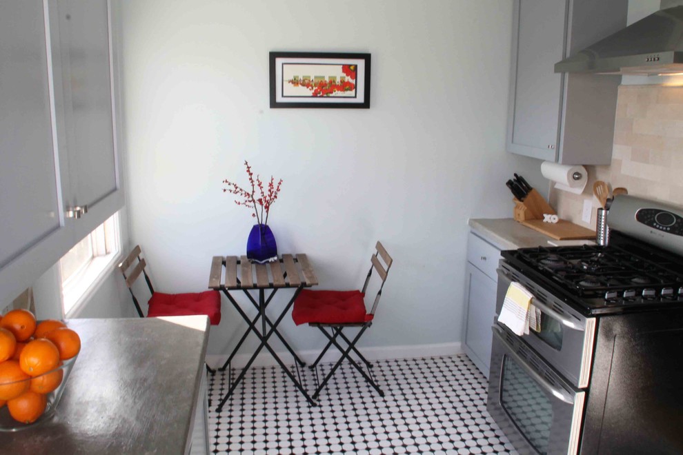 Modern inredning av ett kök, med en undermonterad diskho, öppna hyllor, grå skåp, bänkskiva i betong, beige stänkskydd, stänkskydd i keramik och rostfria vitvaror