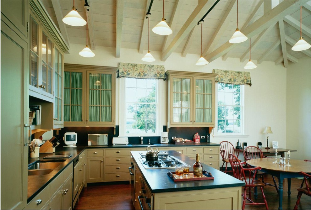 Exempel på ett mellanstort klassiskt kök, med en dubbel diskho, släta luckor, gröna skåp, bänkskiva i täljsten, svart stänkskydd, stänkskydd i sten, rostfria vitvaror, mellanmörkt trägolv och en köksö