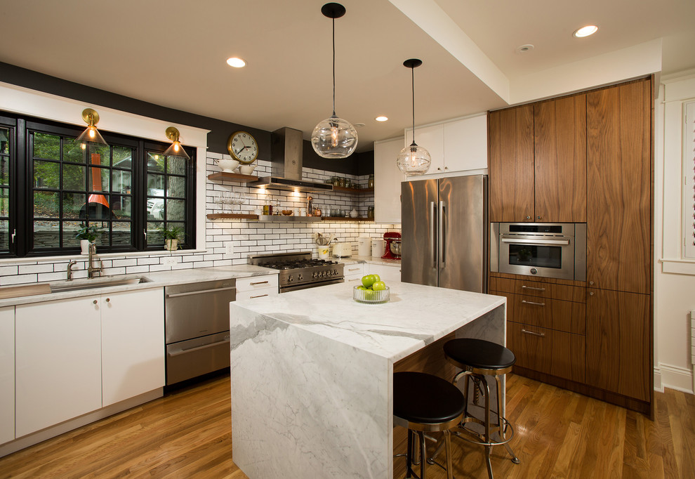 Example of a mid-sized transitional l-shaped light wood floor eat-in kitchen design in DC Metro with an undermount sink, flat-panel cabinets, white cabinets, granite countertops, white backsplash, ceramic backsplash, stainless steel appliances and an island