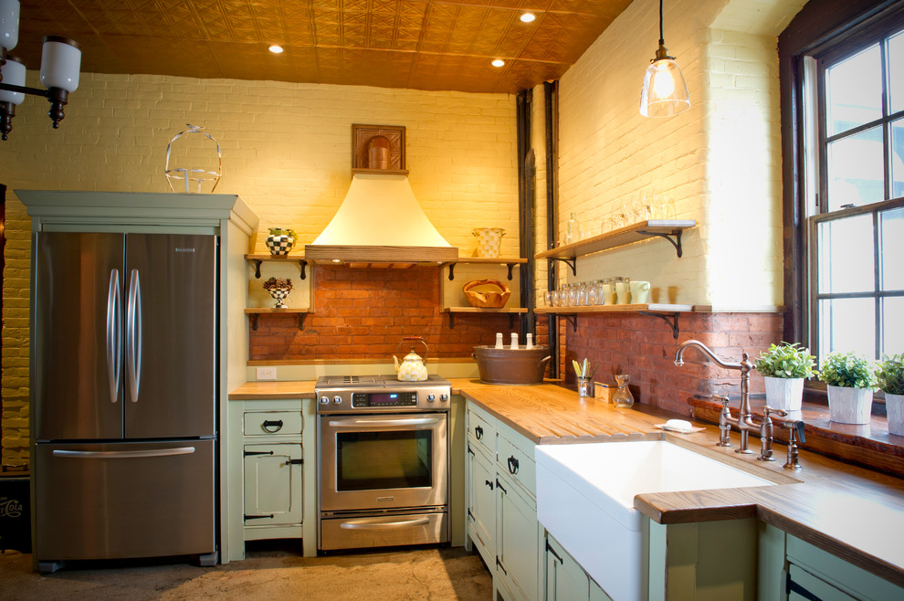 Klassisk inredning av ett kök, med en rustik diskho, träbänkskiva, luckor med profilerade fronter, rostfria vitvaror och skåp i slitet trä