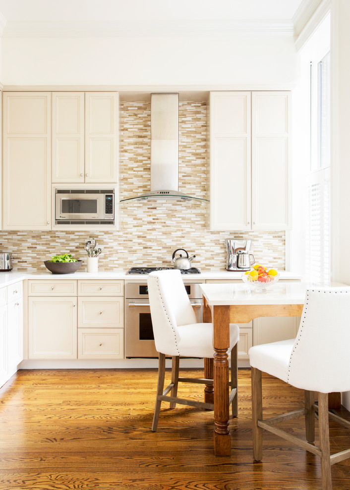 Bild på ett avskilt, mellanstort vintage vit vitt l-kök, med luckor med infälld panel, vita skåp, bänkskiva i koppar, flerfärgad stänkskydd, stänkskydd i glaskakel, rostfria vitvaror och mellanmörkt trägolv