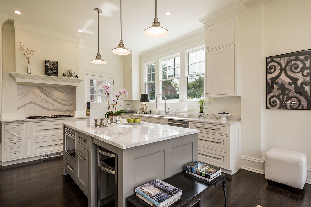 This is an example of a traditional l-shaped kitchen in Other with a submerged sink, shaker cabinets, white cabinets, white splashback, stainless steel appliances, dark hardwood flooring, an island, brown floors and white worktops.
