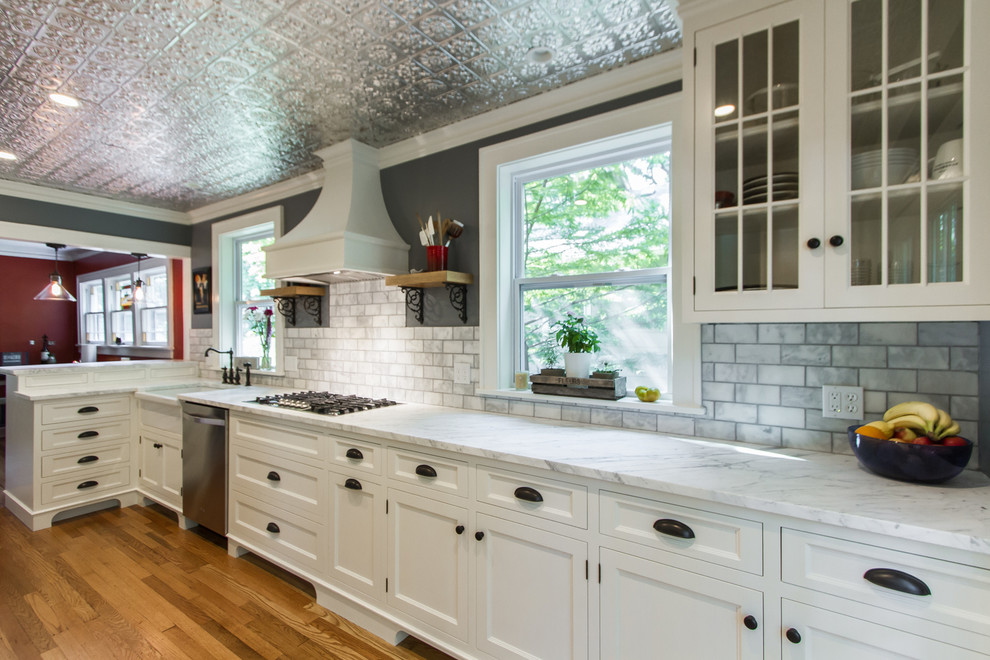Foto på ett mellanstort vintage vit kök, med en halv köksö, vita skåp, marmorbänkskiva, stänkskydd i marmor, rostfria vitvaror, ljust trägolv, en rustik diskho och släta luckor