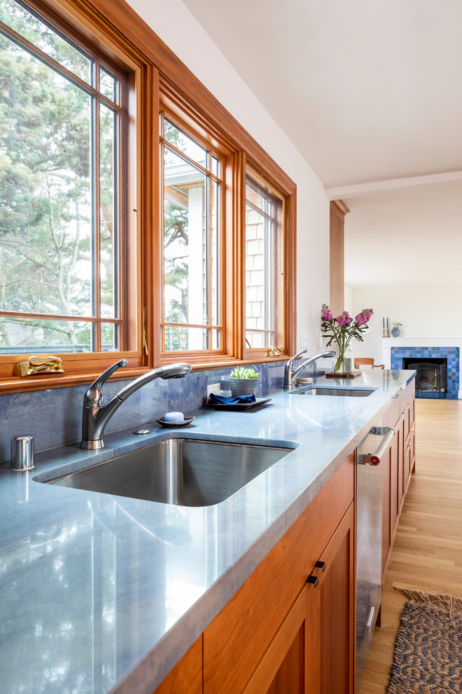 Bild på ett mellanstort vintage blå blått kök, med en undermonterad diskho, skåp i shakerstil, skåp i mellenmörkt trä, granitbänkskiva, blått stänkskydd, stänkskydd i sten, rostfria vitvaror och ljust trägolv