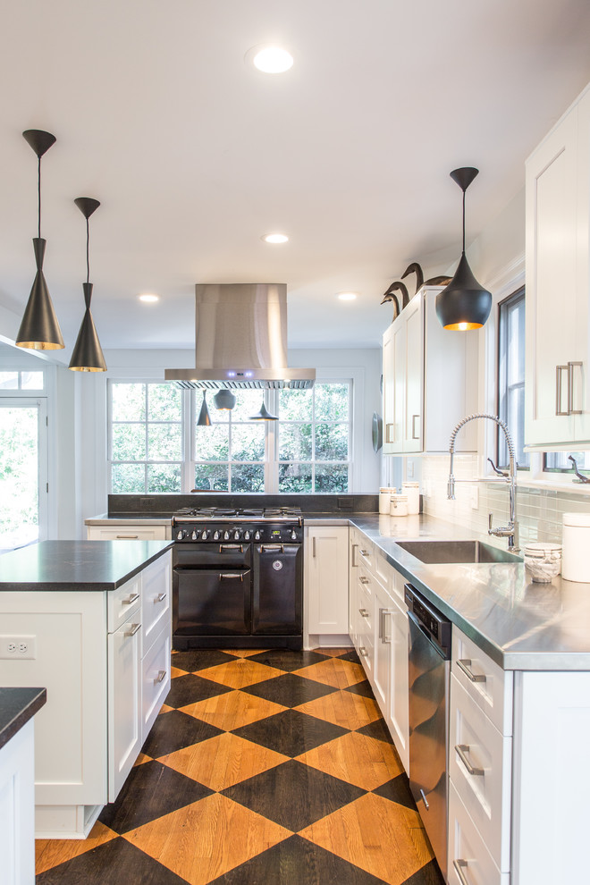 Exempel på ett avskilt klassiskt svart svart u-kök, med skåp i shakerstil, vita skåp, bänkskiva i rostfritt stål, vitt stänkskydd, stänkskydd i tunnelbanekakel, rostfria vitvaror, ljust trägolv, en köksö, flerfärgat golv och en integrerad diskho