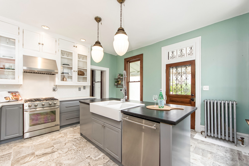Inspiration for a mid-sized transitional l-shaped travertine floor enclosed kitchen remodel in Columbus with raised-panel cabinets, gray cabinets, marble countertops, white backsplash, ceramic backsplash, stainless steel appliances and an island