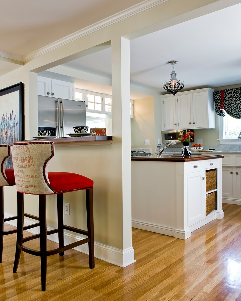 Example of a mid-sized classic u-shaped enclosed kitchen design in Boston with shaker cabinets, white cabinets, wood countertops and an island