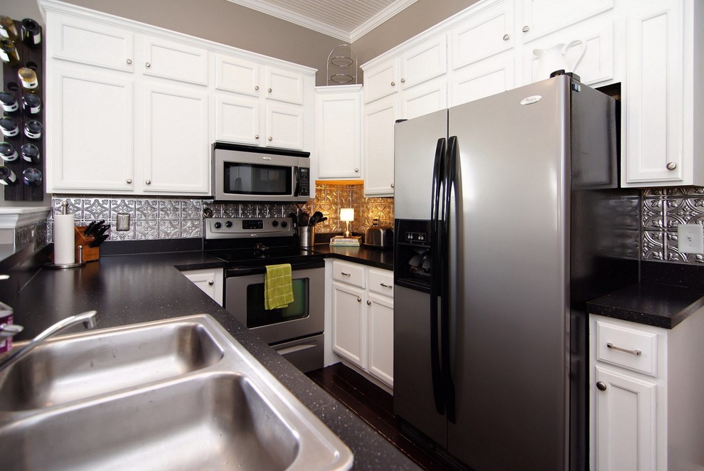 Exempel på ett avskilt, litet modernt svart svart u-kök, med en dubbel diskho, luckor med infälld panel, vita skåp, laminatbänkskiva, stänkskydd med metallisk yta, stänkskydd i metallkakel, rostfria vitvaror, mörkt trägolv, en halv köksö och brunt golv