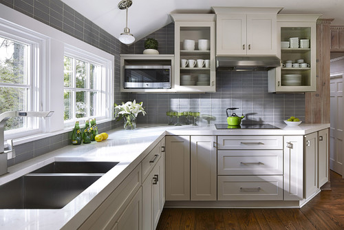Bright kitchen with gray RTA cabinets, glass-front uppers, and quartz countertops.