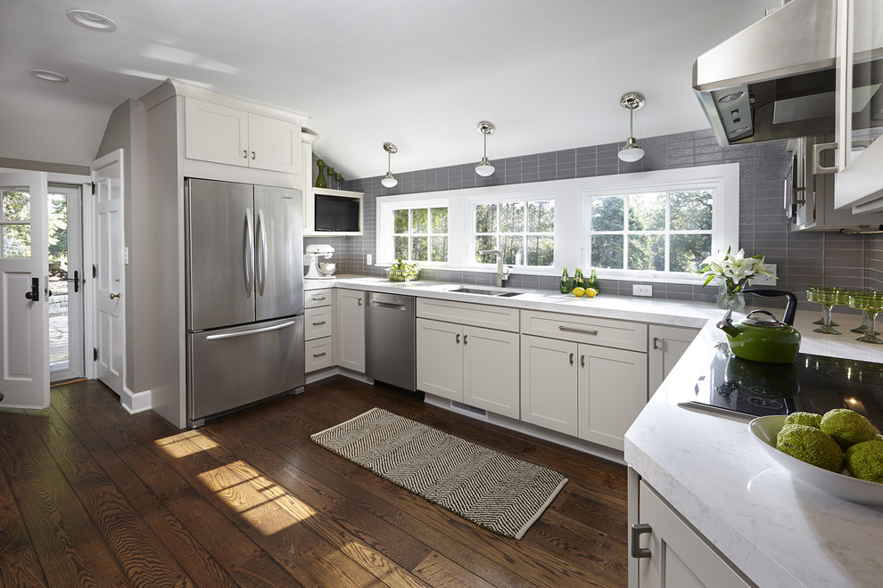 Mid-sized transitional u-shaped medium tone wood floor eat-in kitchen photo in Atlanta with an undermount sink, shaker cabinets, gray cabinets, gray backsplash, glass tile backsplash, stainless steel appliances and no island