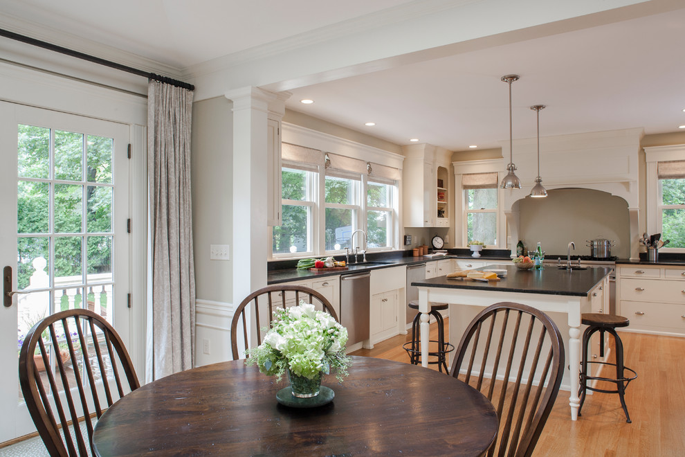 Inspiration for a large transitional l-shaped light wood floor open concept kitchen remodel in Boston with an undermount sink, flat-panel cabinets, white cabinets, granite countertops, black backsplash, stone slab backsplash, stainless steel appliances and an island