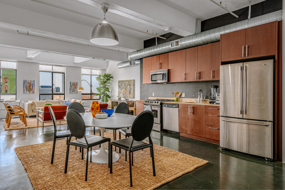 Medium sized urban single-wall open plan kitchen in Los Angeles with concrete flooring, grey floors, a submerged sink, flat-panel cabinets, medium wood cabinets, stainless steel appliances, no island and beige worktops.